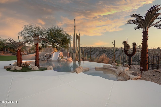 pool at dusk with a patio and a jacuzzi