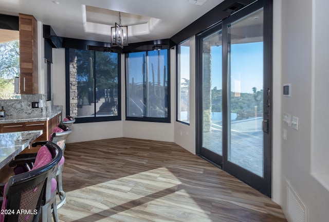 sunroom / solarium with a chandelier, a tray ceiling, and a wealth of natural light