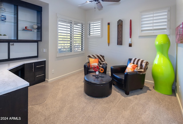 living area with light carpet and ceiling fan