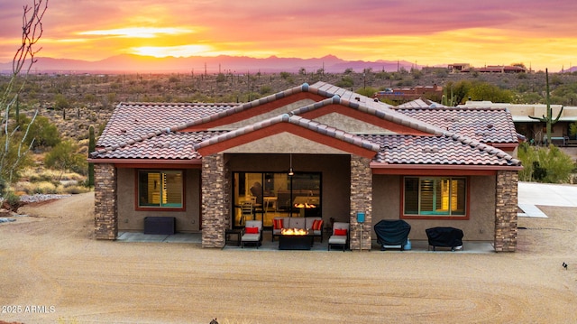 back house at dusk with an outdoor living space and a patio