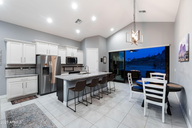 kitchen with stainless steel appliances, light stone countertops, pendant lighting, and white cabinets