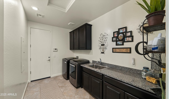 washroom with light tile patterned flooring, sink, washing machine and clothes dryer, and cabinets