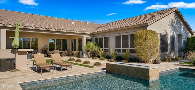 rear view of property with ceiling fan, a swimming pool with hot tub, and a patio