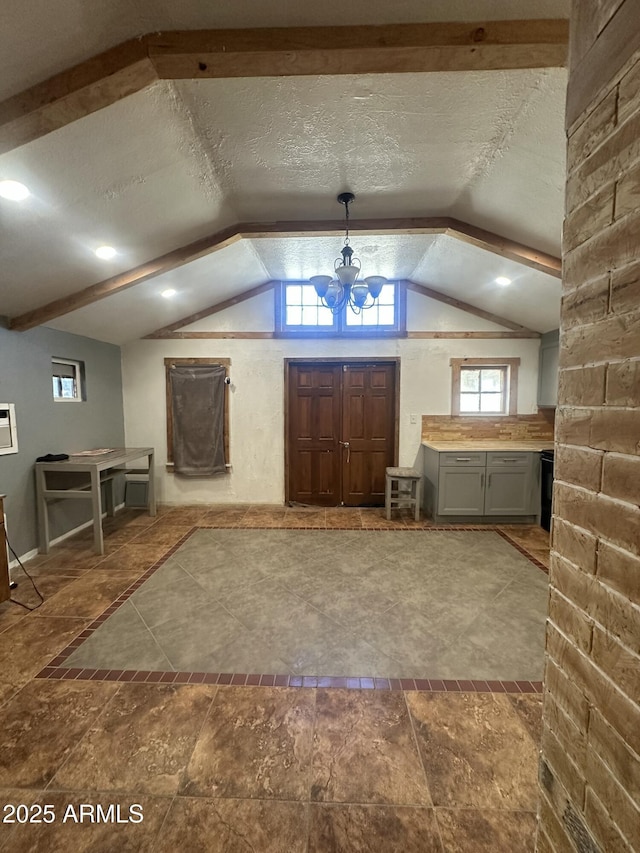 foyer featuring lofted ceiling, a chandelier, and a textured ceiling