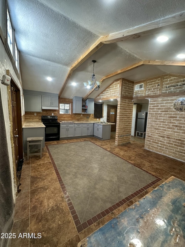 kitchen featuring gray cabinetry, hanging light fixtures, electric range, and lofted ceiling