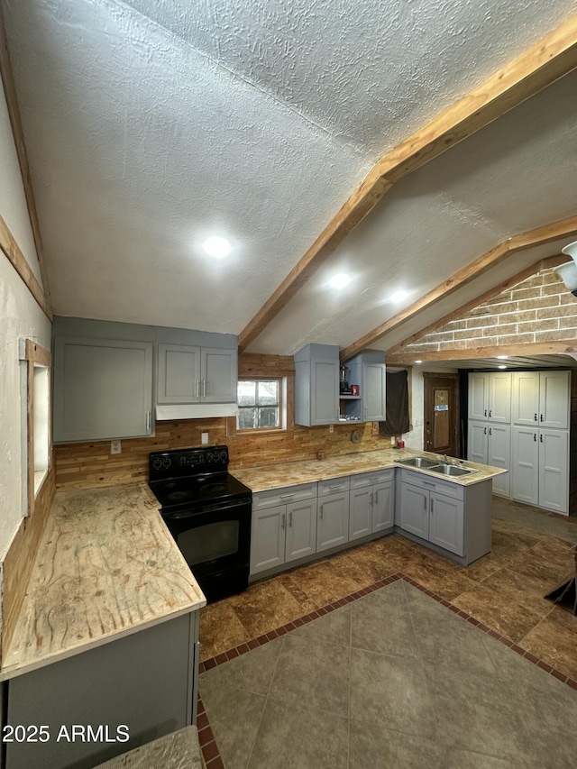 kitchen with lofted ceiling with beams, black range with electric stovetop, gray cabinetry, and a textured ceiling