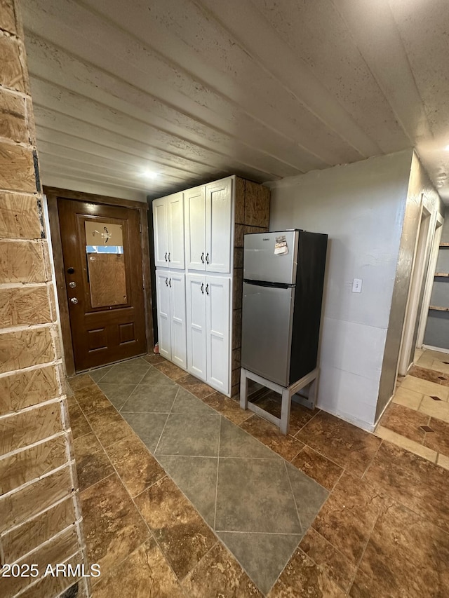 kitchen featuring white cabinetry, wooden ceiling, and stainless steel fridge