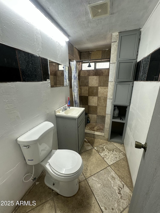 bathroom featuring vanity, toilet, curtained shower, and a textured ceiling