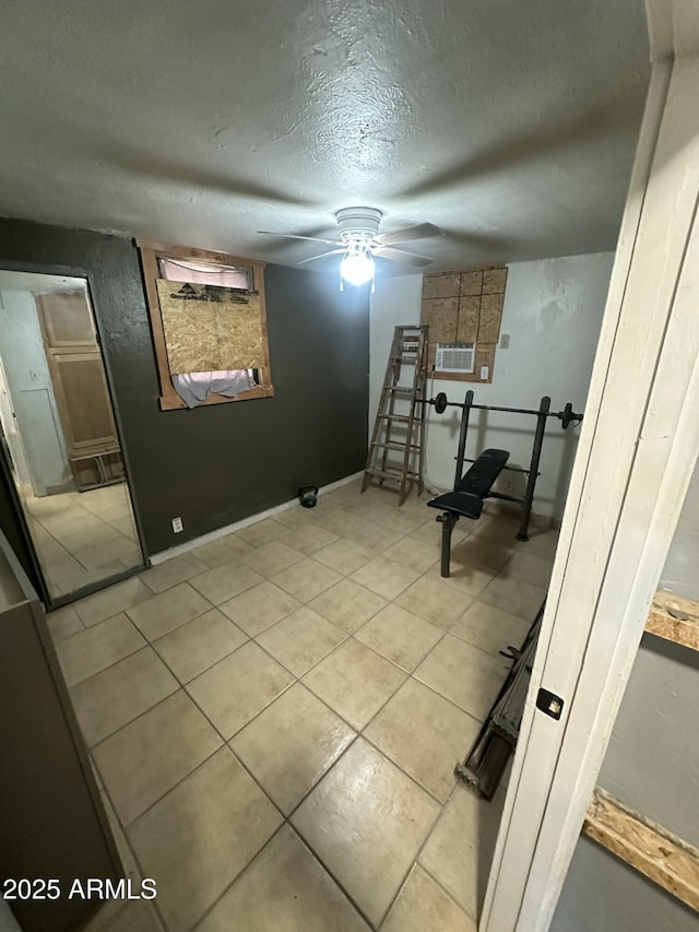 workout room with ceiling fan, light tile patterned floors, and a textured ceiling