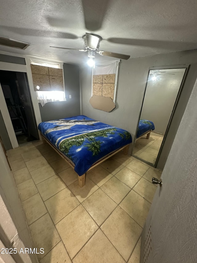 tiled bedroom featuring ceiling fan and a textured ceiling