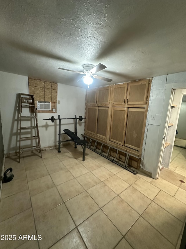 basement featuring ceiling fan, an AC wall unit, a textured ceiling, and light tile patterned floors