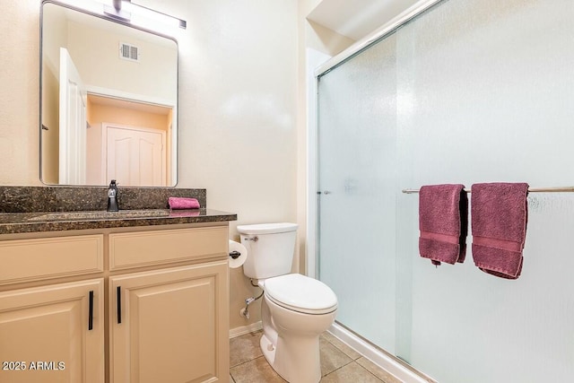 bathroom featuring tile patterned floors, a shower with door, vanity, and toilet