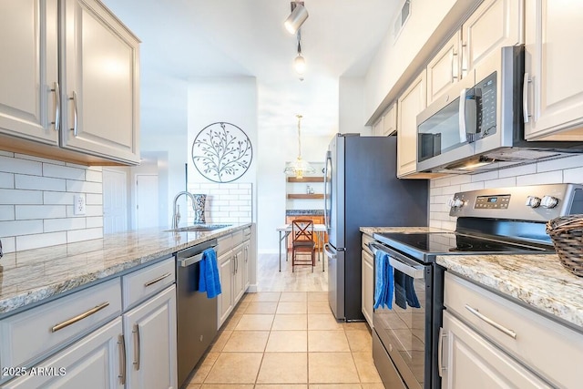 kitchen with white cabinets, sink, light tile patterned floors, appliances with stainless steel finishes, and light stone counters