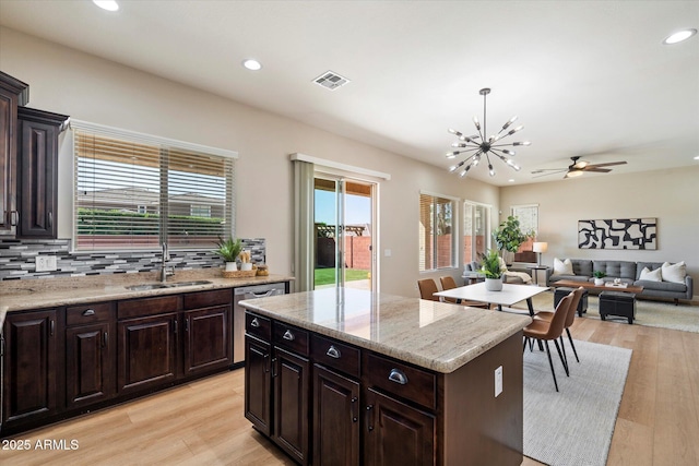 kitchen featuring backsplash, a healthy amount of sunlight, light wood-type flooring, and a sink