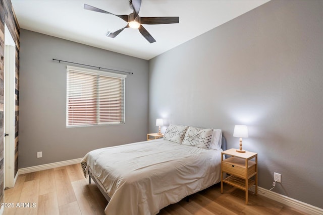 bedroom with light wood finished floors, a ceiling fan, and baseboards