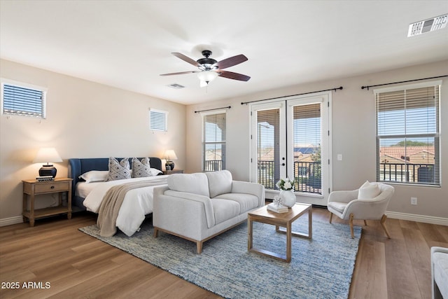 bedroom featuring multiple windows, wood finished floors, baseboards, and access to exterior