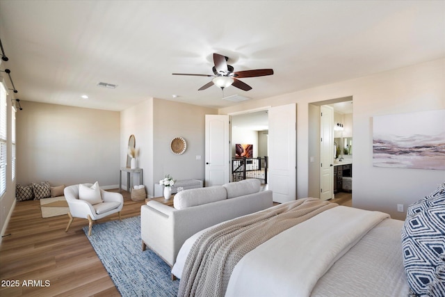 bedroom with visible vents, a barn door, light wood-style floors, and ceiling fan