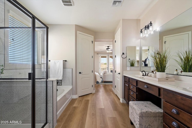 bathroom featuring wood finished floors, visible vents, double vanity, ensuite bathroom, and a garden tub