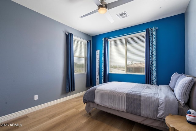 bedroom with visible vents, baseboards, wood finished floors, and a ceiling fan