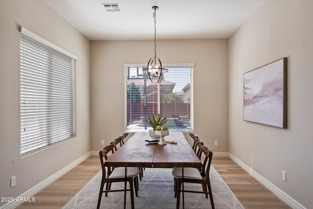 dining area with light wood finished floors, visible vents, and baseboards