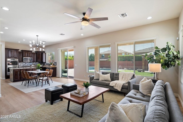 living room with light wood finished floors, visible vents, recessed lighting, and ceiling fan with notable chandelier