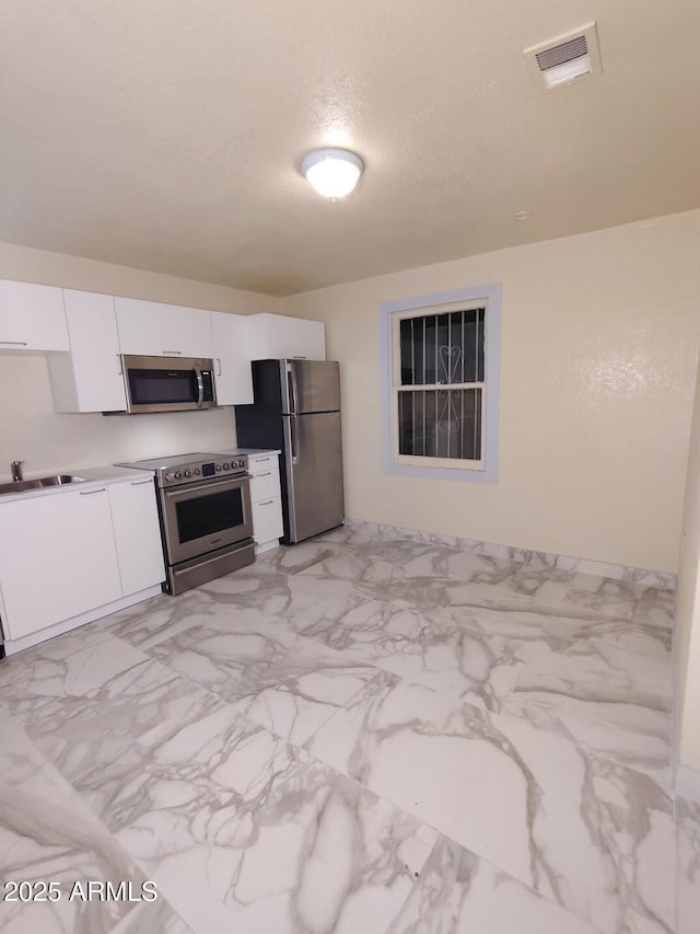 126 N 9th Ave, Phoenix, AZ 85007 - kitchen with stainless steel appliances, white cabinetry, light marble finish flooring, and light countertops