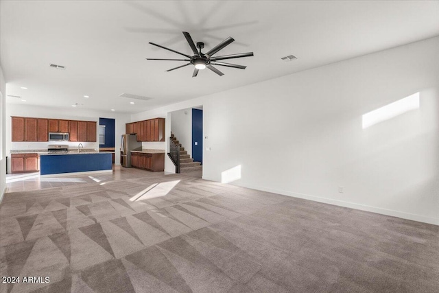 unfurnished living room featuring light carpet, ceiling fan, and sink