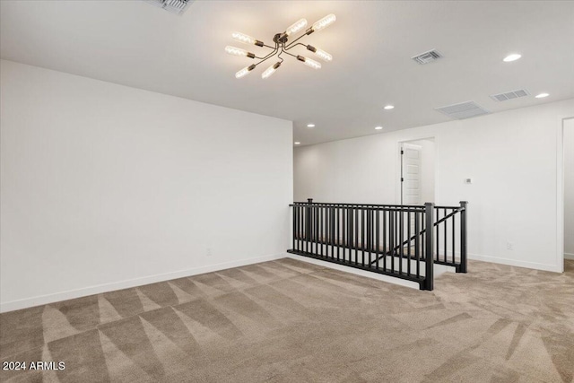 carpeted spare room featuring a notable chandelier