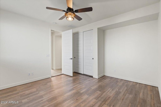 unfurnished bedroom with hardwood / wood-style floors, a closet, and ceiling fan