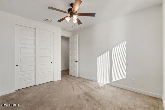 unfurnished bedroom featuring ceiling fan, a closet, and light colored carpet