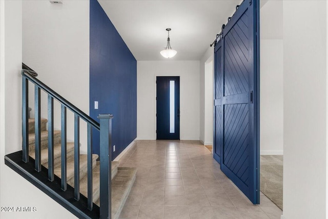 entrance foyer with a barn door and light tile patterned floors