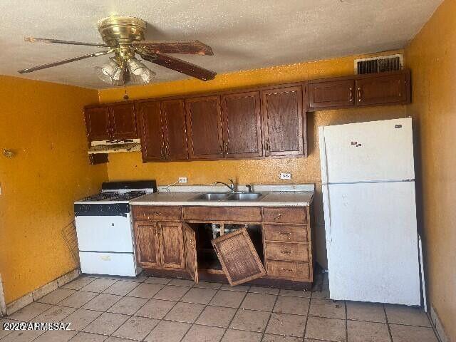 kitchen with white appliances, visible vents, a ceiling fan, a sink, and exhaust hood