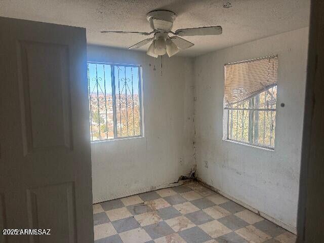 empty room with light floors, a textured ceiling, and a ceiling fan