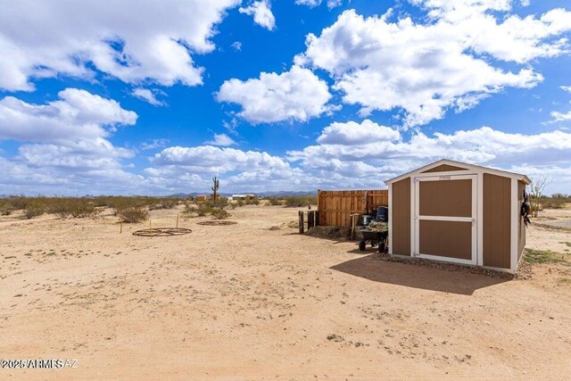 view of yard featuring a storage shed, fence, and an outbuilding