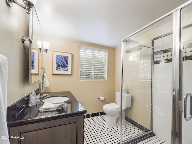 bathroom featuring toilet, vanity, tile patterned flooring, and a shower with door