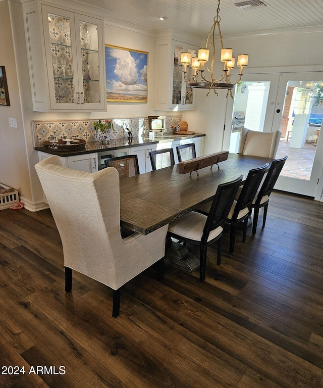 dining room featuring dark wood-type flooring, a chandelier, and crown molding