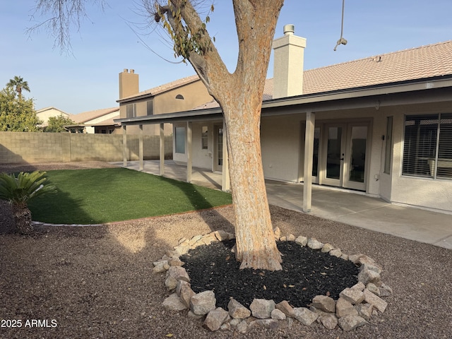 back of property featuring french doors, a lawn, and a patio area