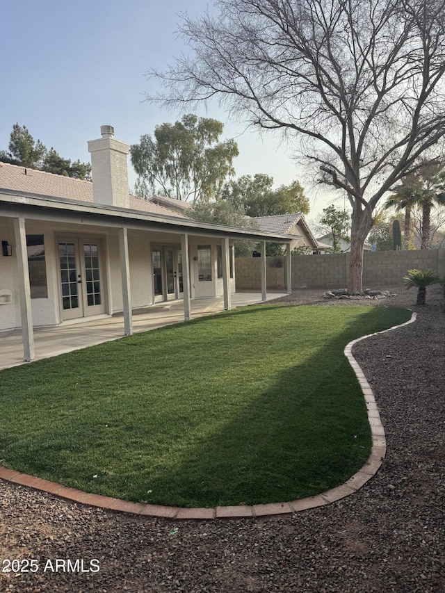 rear view of house with a patio, a lawn, and french doors