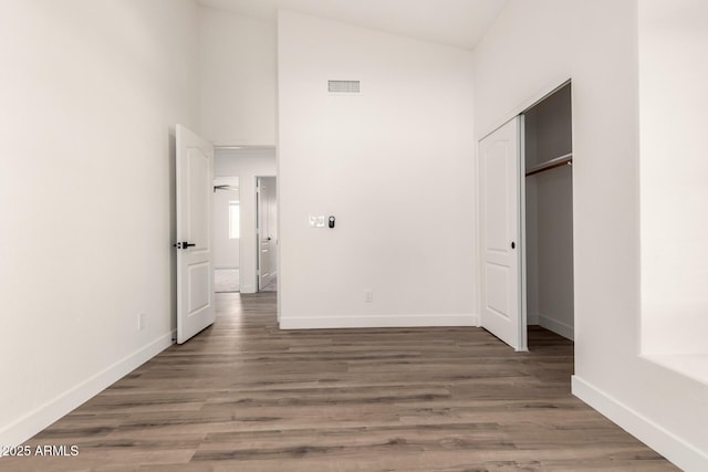 unfurnished bedroom featuring dark wood-type flooring, high vaulted ceiling, and a closet