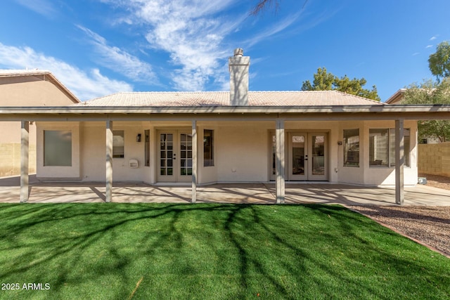 rear view of property featuring a patio, a lawn, and french doors