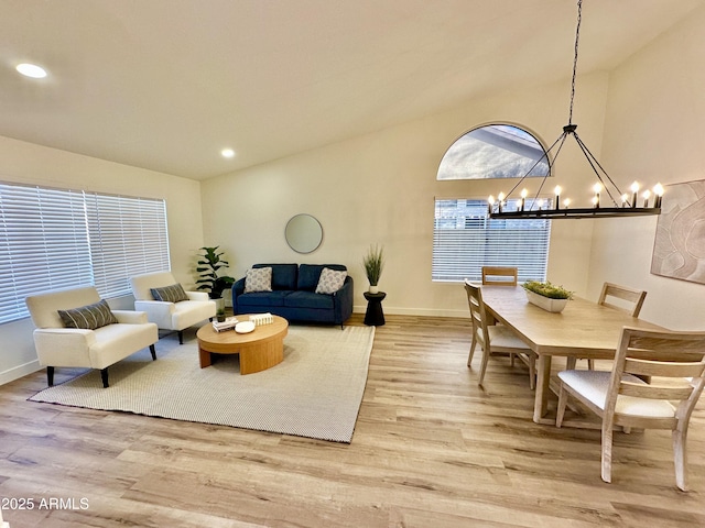 living room featuring an inviting chandelier, vaulted ceiling, and light wood-type flooring