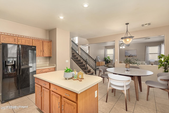 9207 W Kirby Ave, Tolleson, AZ 85353 - kitchen featuring black fridge with ice dispenser, light tile patterned floors, a ceiling fan, light countertops, and a kitchen island
