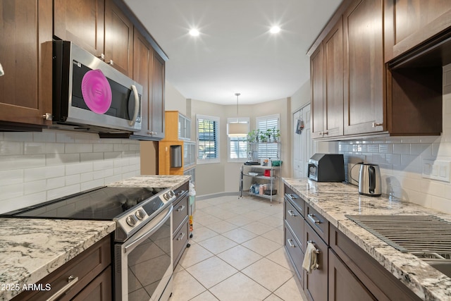 kitchen with stainless steel appliances, pendant lighting, light stone counters, and decorative backsplash