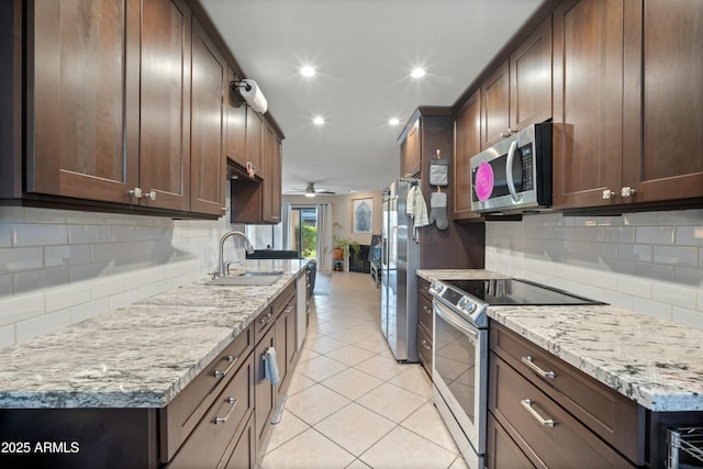 kitchen featuring stainless steel appliances, sink, light stone counters, and decorative backsplash