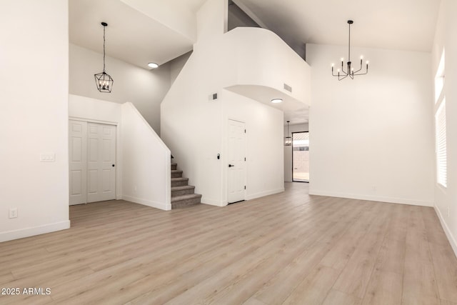 8928 E Crescent Ave, Mesa, AZ 85208 - unfurnished living room with a chandelier, high vaulted ceiling, stairway, light wood finished floors, and baseboards