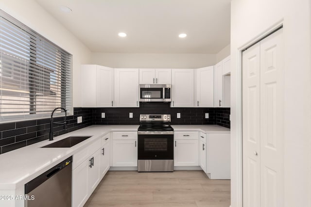8928 E Crescent Ave, Mesa, AZ 85208 - kitchen featuring stainless steel appliances, a sink, tasteful backsplash, white cabinets, and light wood-style flooring