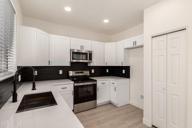 8928 E Crescent Ave, Mesa, AZ 85208 - kitchen with stainless steel appliances, a sink, decorative backsplash, white cabinets, and light wood-style flooring