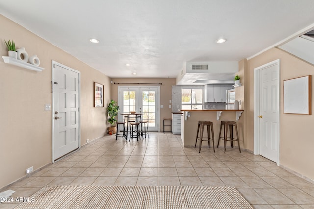 kitchen with a kitchen breakfast bar, french doors, light tile patterned floors, and kitchen peninsula