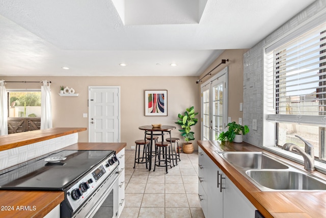 kitchen featuring plenty of natural light, electric stove, and white cabinets