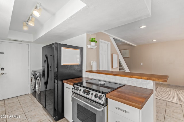 kitchen featuring washing machine and dryer, white cabinetry, stainless steel range with electric stovetop, and light tile patterned flooring